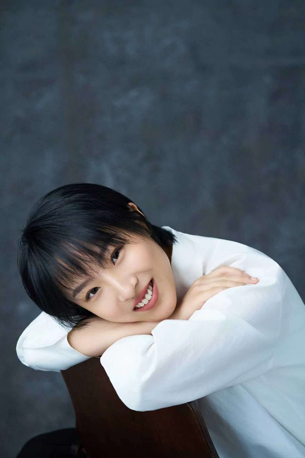 Smiling, arms folded over the back of a chair