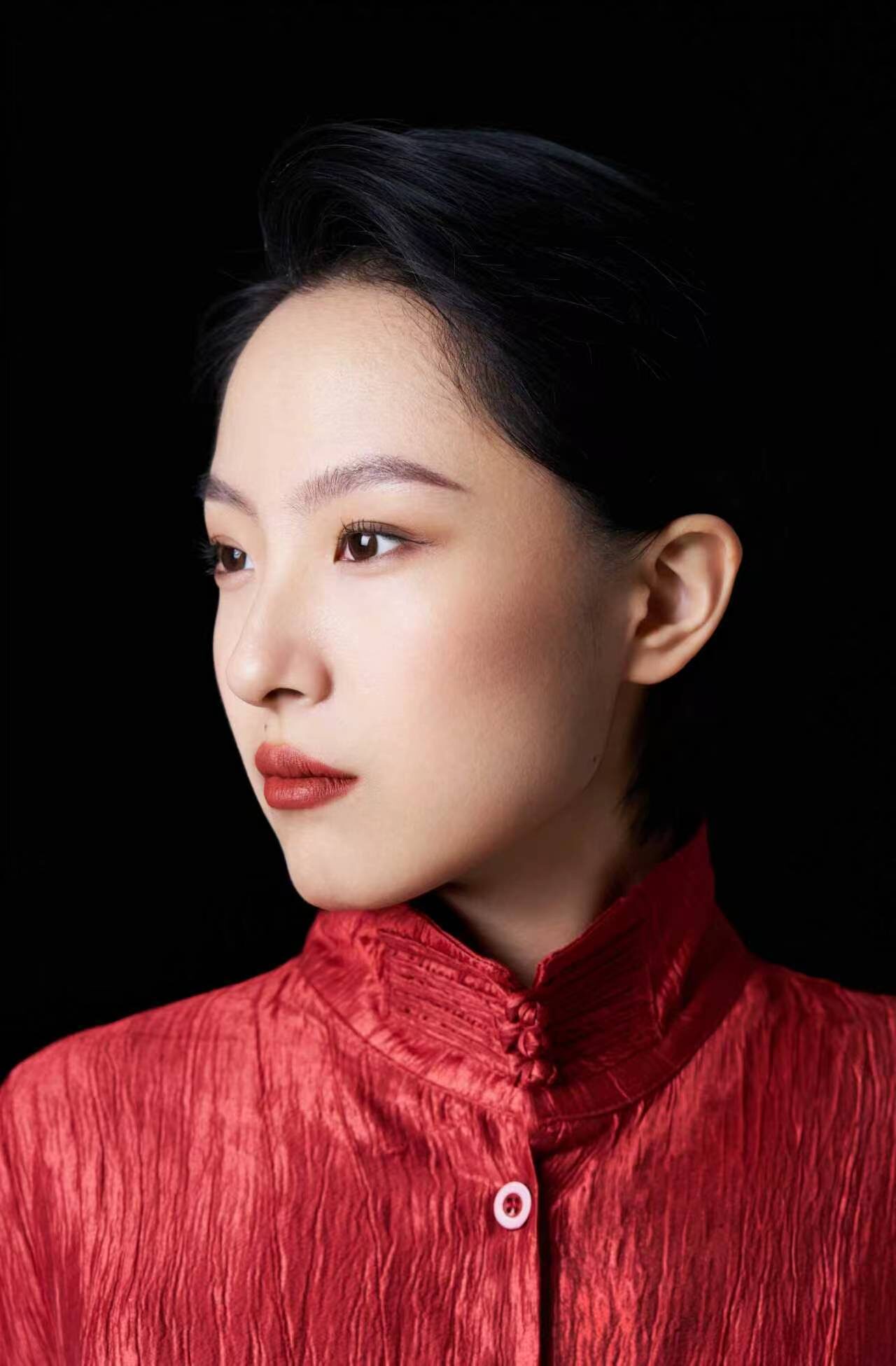 Xiaoru Wen in a red silk jacket, in three-quarter profile